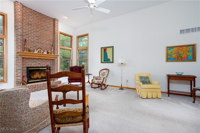 living room with a brick fireplace, carpet, and ceiling fan