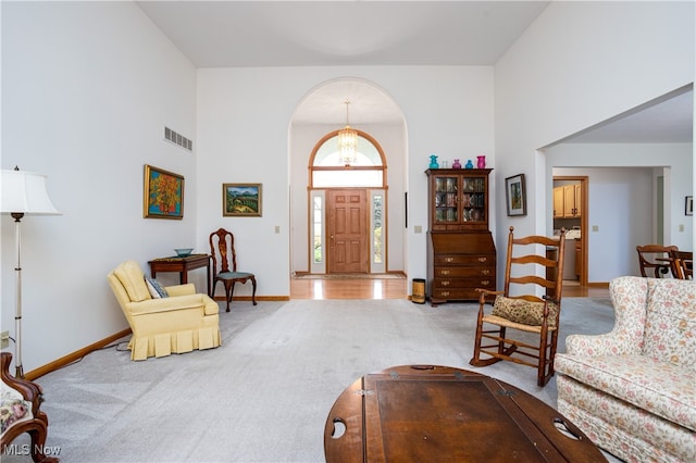 carpeted living room featuring a towering ceiling and a chandelier