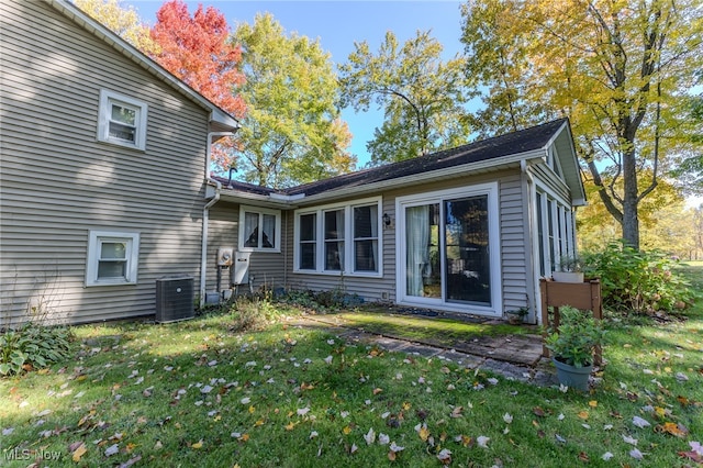 rear view of house featuring central AC unit and a yard