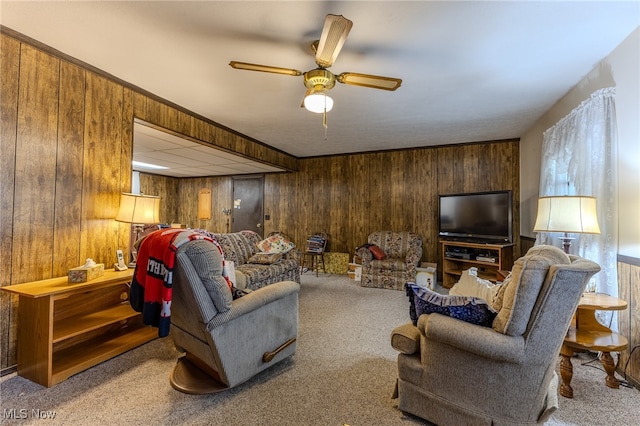 carpeted living room featuring ornamental molding, wood walls, and ceiling fan