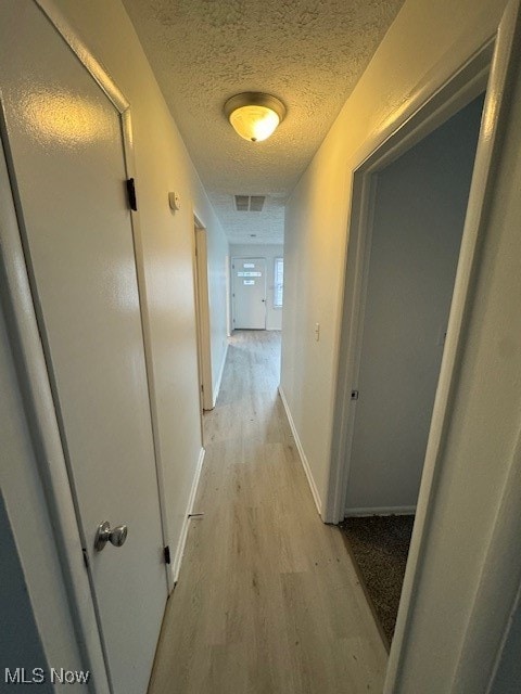 hall featuring a textured ceiling and light hardwood / wood-style flooring