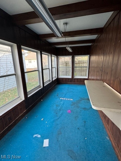 unfurnished sunroom with beamed ceiling and a healthy amount of sunlight