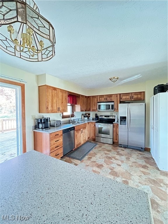 kitchen featuring appliances with stainless steel finishes, decorative light fixtures, a textured ceiling, sink, and a chandelier