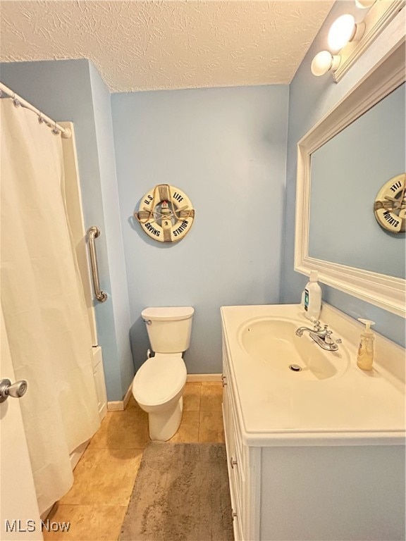 bathroom with toilet, vanity, a textured ceiling, and tile patterned flooring