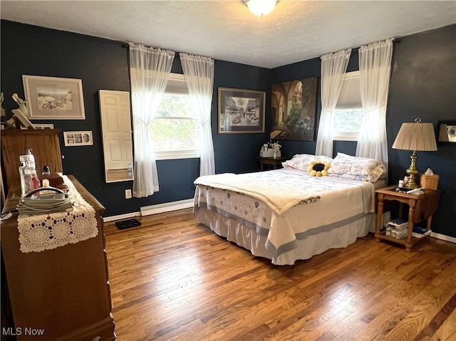 bedroom with a baseboard radiator and hardwood / wood-style flooring