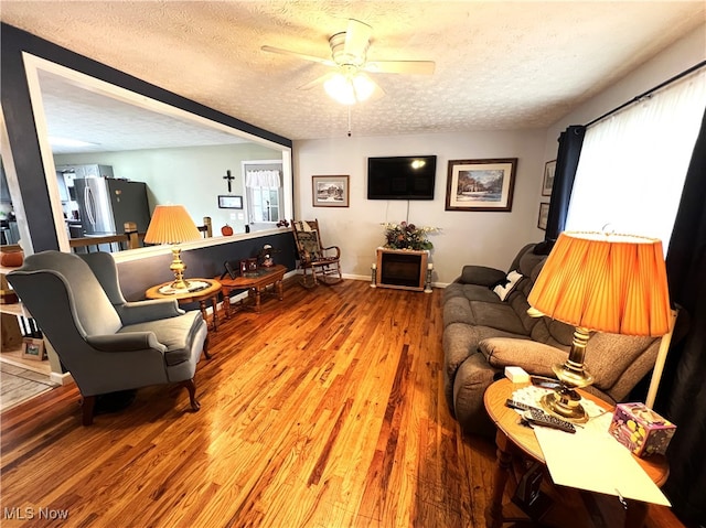 living room with a textured ceiling, hardwood / wood-style floors, and ceiling fan