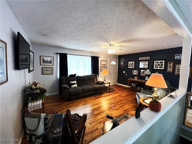 living room with a textured ceiling, ceiling fan, and hardwood / wood-style flooring