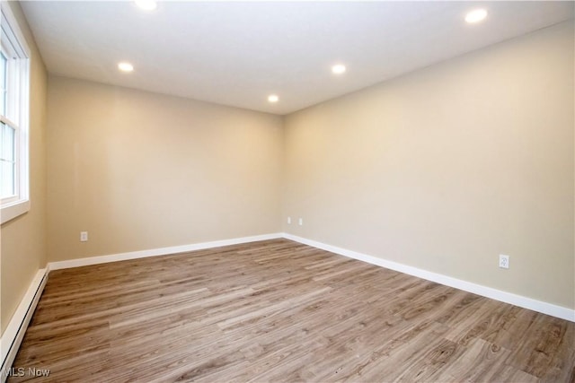 empty room with light hardwood / wood-style floors and baseboard heating