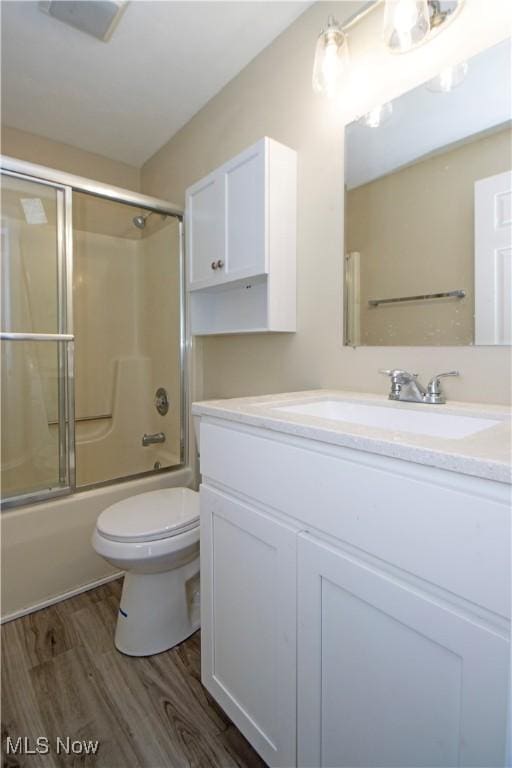 full bathroom with toilet, vanity, wood-type flooring, and combined bath / shower with glass door