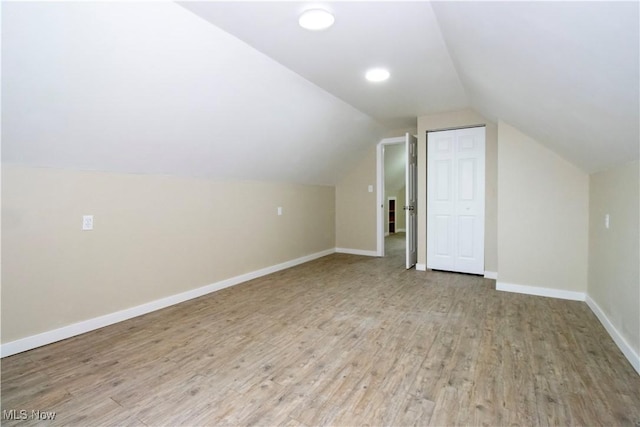 additional living space with light hardwood / wood-style floors and vaulted ceiling