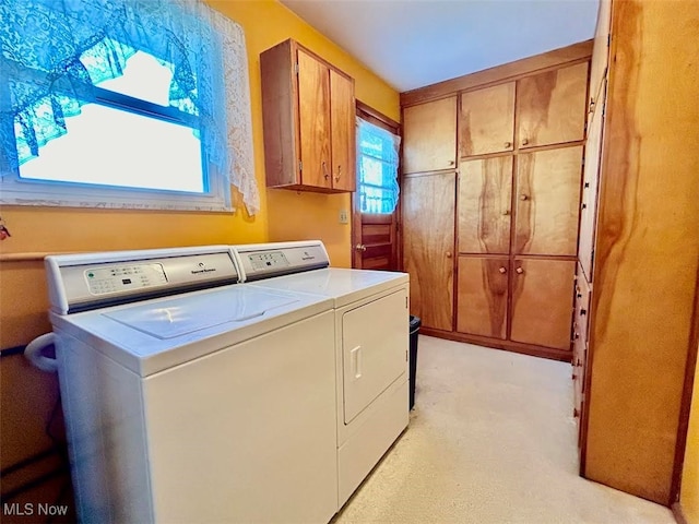 clothes washing area featuring cabinets and washer and dryer