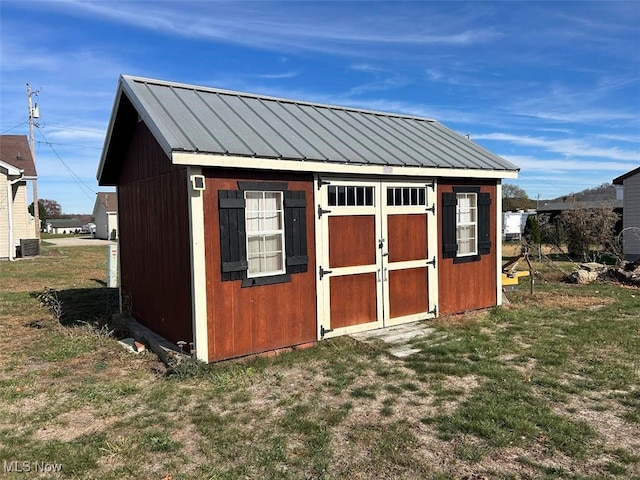 view of outdoor structure featuring central air condition unit and a yard