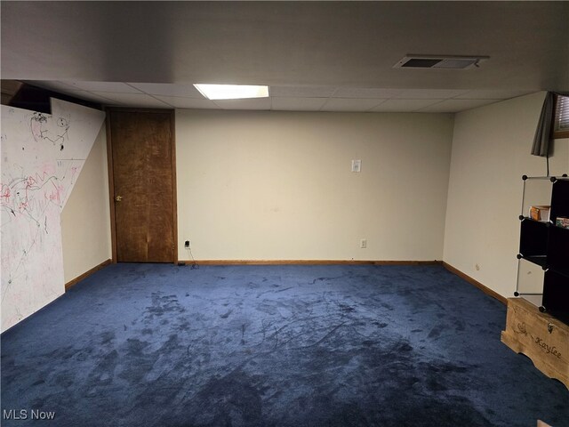 basement featuring a paneled ceiling and dark carpet