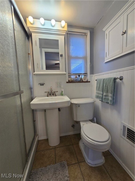 bathroom featuring a shower with shower door, tile patterned floors, and toilet