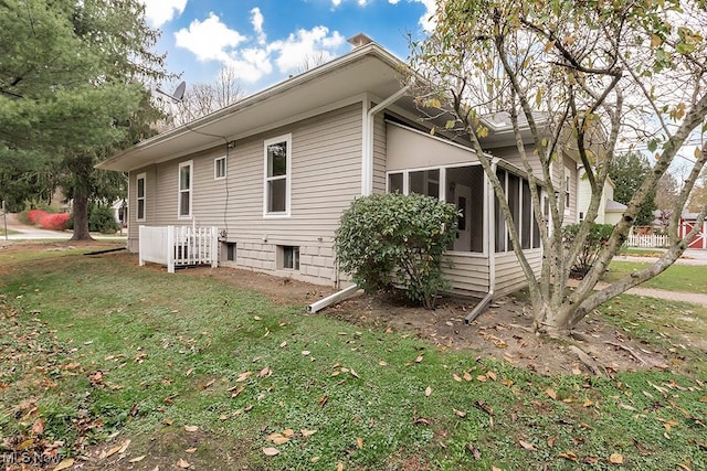 view of side of home with a lawn and a sunroom