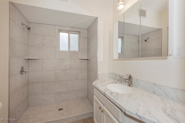 bathroom featuring hardwood / wood-style floors, tiled shower, and vanity