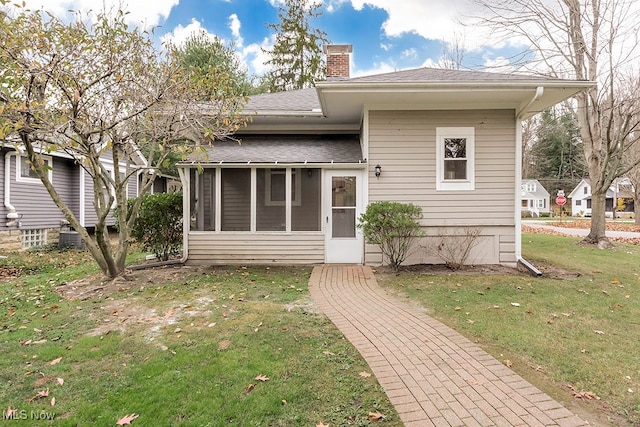 back of property featuring a sunroom and a lawn