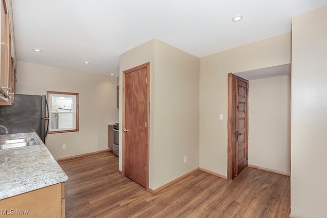 kitchen with dark hardwood / wood-style flooring, sink, stainless steel range oven, and black refrigerator