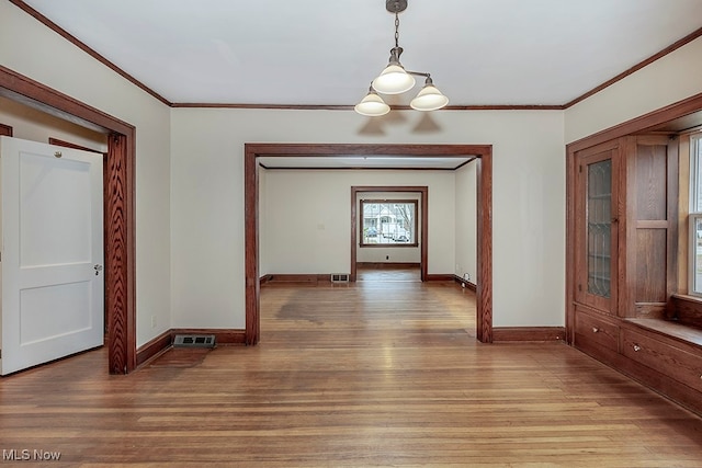 unfurnished dining area with light hardwood / wood-style flooring, crown molding, and a notable chandelier