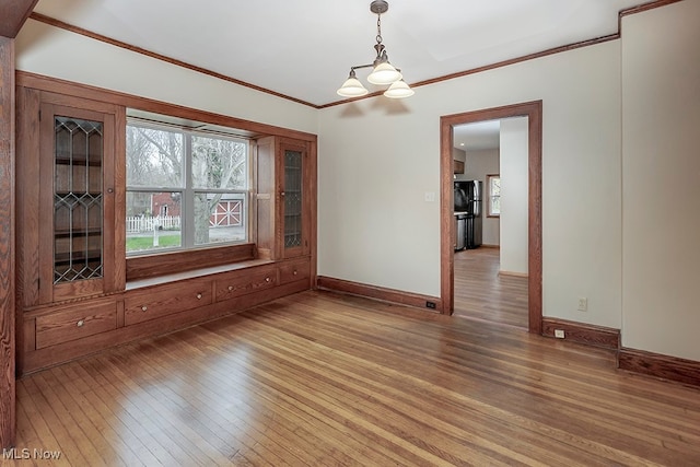 unfurnished dining area with hardwood / wood-style floors, a notable chandelier, and ornamental molding