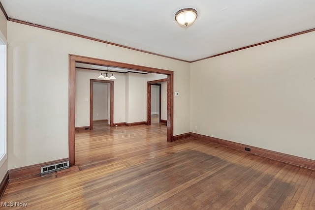 empty room with ornamental molding and hardwood / wood-style flooring