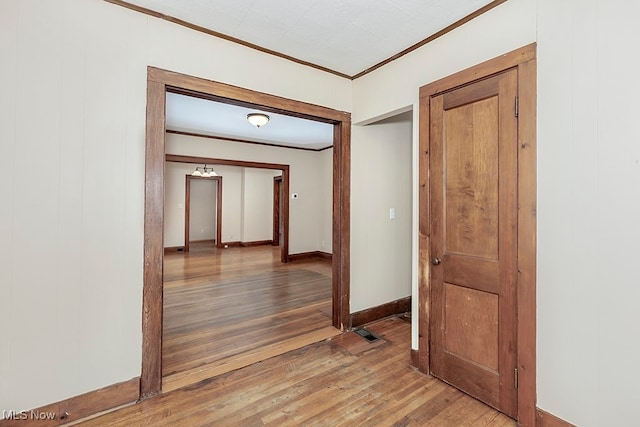 hallway with ornamental molding, hardwood / wood-style floors, and wood walls