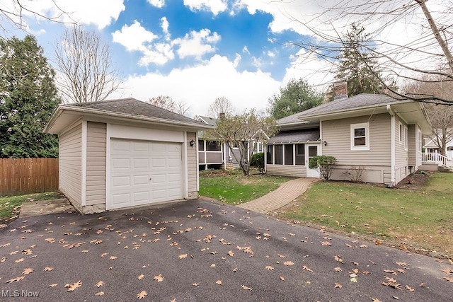 view of front of home featuring a front yard, a sunroom, and a garage