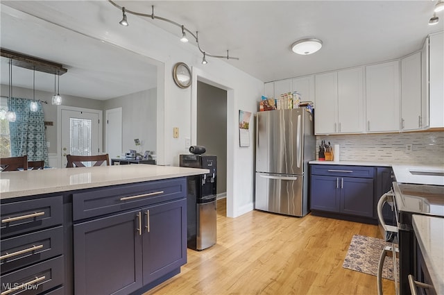 kitchen featuring light hardwood / wood-style floors, stainless steel refrigerator, white cabinetry, decorative light fixtures, and stove