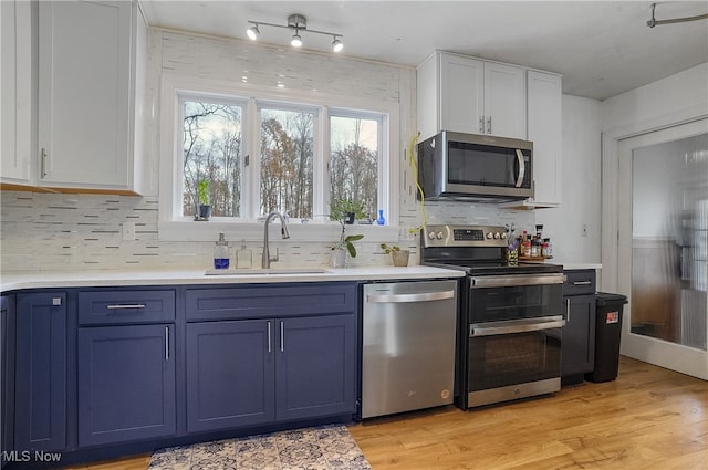 kitchen featuring stainless steel appliances, sink, light hardwood / wood-style flooring, blue cabinets, and white cabinets