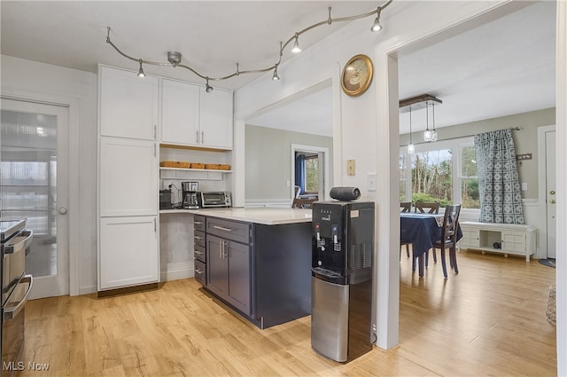 kitchen with hanging light fixtures, light hardwood / wood-style floors, white cabinetry, and a wealth of natural light