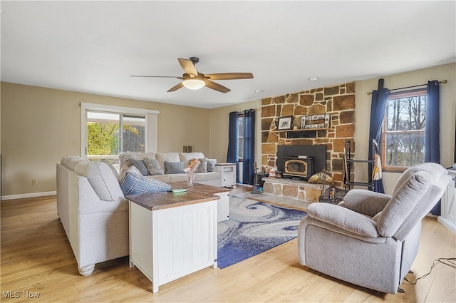 living room with ceiling fan, light hardwood / wood-style flooring, and a wood stove