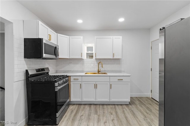 kitchen featuring stainless steel appliances, white cabinetry, sink, light wood-type flooring, and decorative backsplash