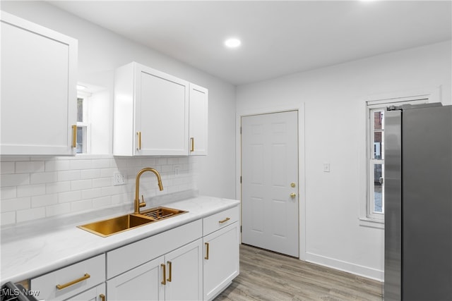 kitchen featuring white cabinetry, sink, stainless steel fridge, and light hardwood / wood-style flooring