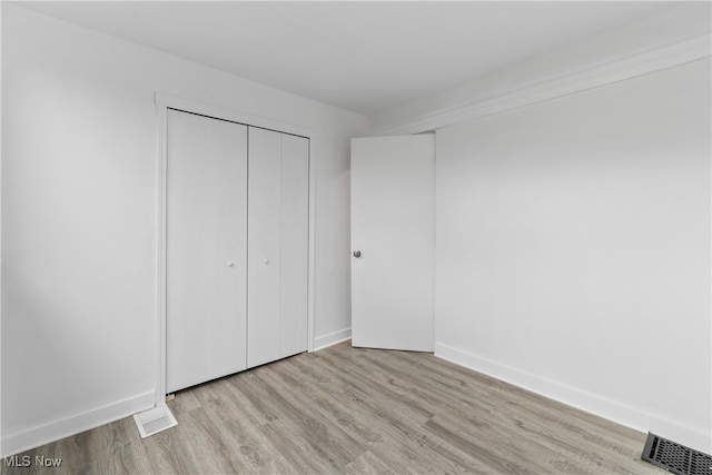 unfurnished bedroom featuring light hardwood / wood-style flooring and a closet