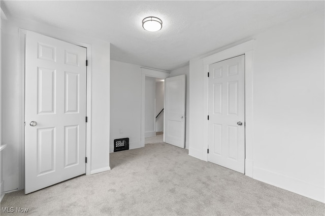 unfurnished bedroom with a textured ceiling and light colored carpet