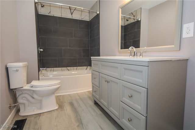 full bathroom featuring toilet, tiled shower / bath combo, vanity, and wood-type flooring