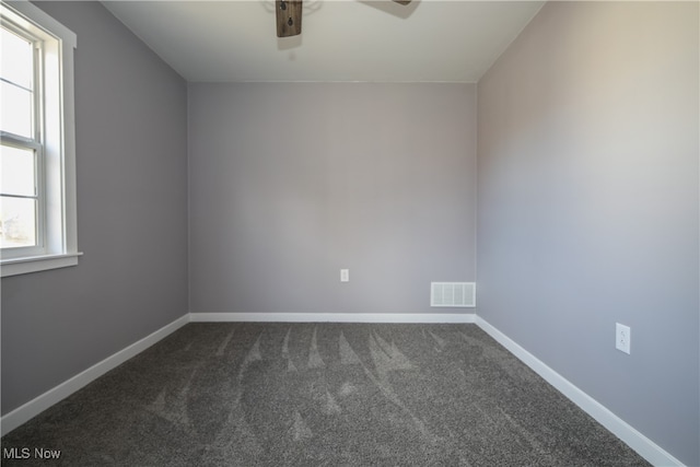 spare room featuring dark colored carpet