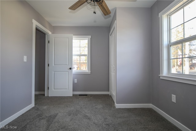 unfurnished bedroom with a closet, dark colored carpet, and ceiling fan