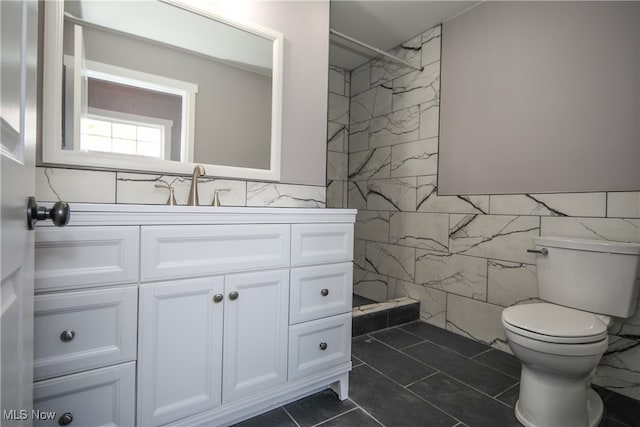 bathroom featuring tile walls, walk in shower, vanity, tile patterned flooring, and toilet