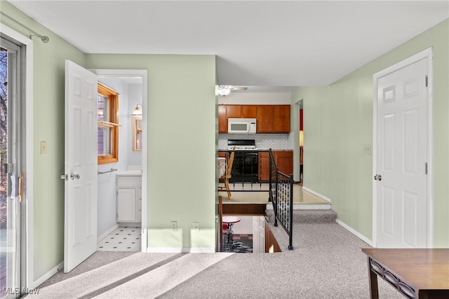 interior space with decorative backsplash, light colored carpet, and electric stove