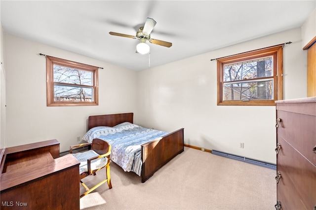 carpeted bedroom featuring ceiling fan, multiple windows, and a baseboard radiator