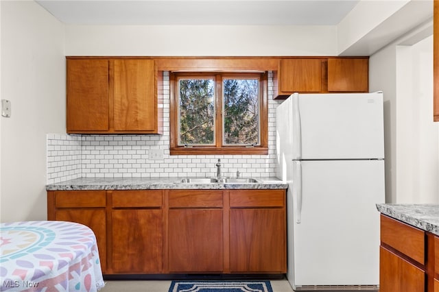 kitchen featuring tasteful backsplash, sink, light stone counters, and white fridge