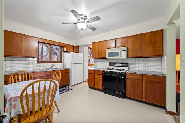 kitchen with sink, light stone counters, tasteful backsplash, ceiling fan, and white appliances