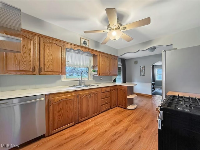 kitchen with kitchen peninsula, light hardwood / wood-style floors, sink, ceiling fan, and appliances with stainless steel finishes