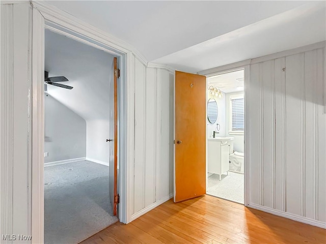 unfurnished room with sink, light hardwood / wood-style floors, and vaulted ceiling