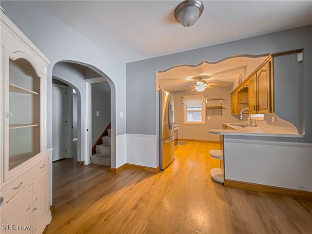 kitchen featuring sink, ceiling fan, stainless steel refrigerator, and light hardwood / wood-style floors