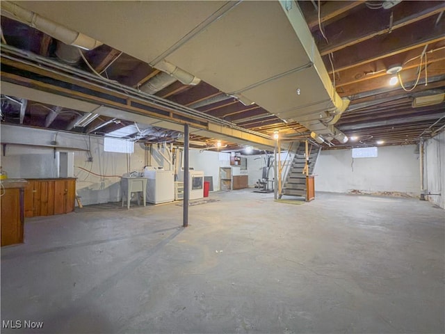 basement featuring a healthy amount of sunlight, sink, and separate washer and dryer