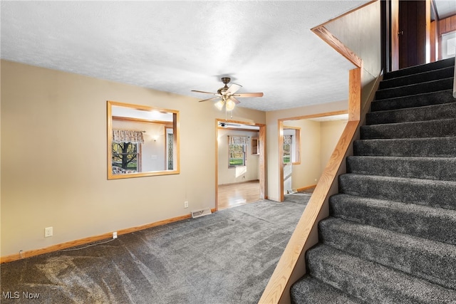 stairs featuring ceiling fan, a textured ceiling, and carpet