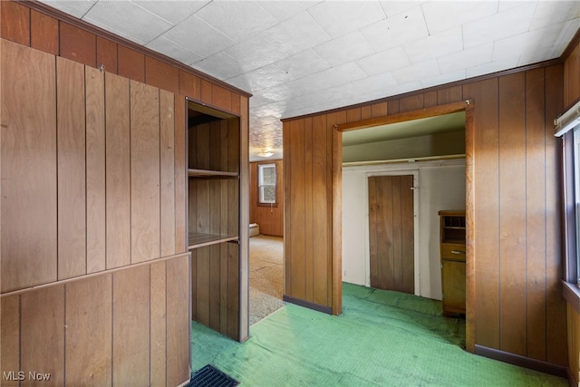 hallway with wood walls and light carpet