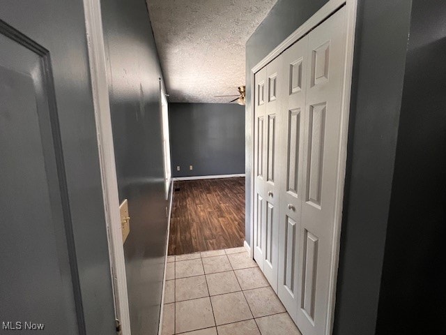 hall with light hardwood / wood-style floors and a textured ceiling